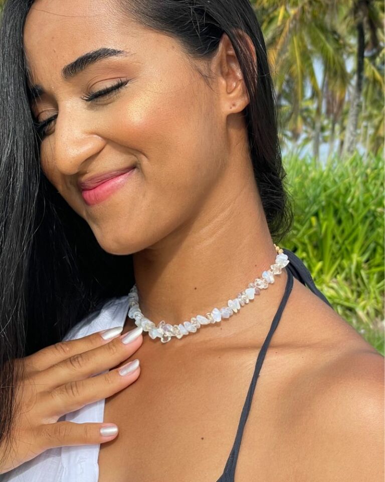 Mulher usando choker Pedra da Lua em meio à natureza tropical.