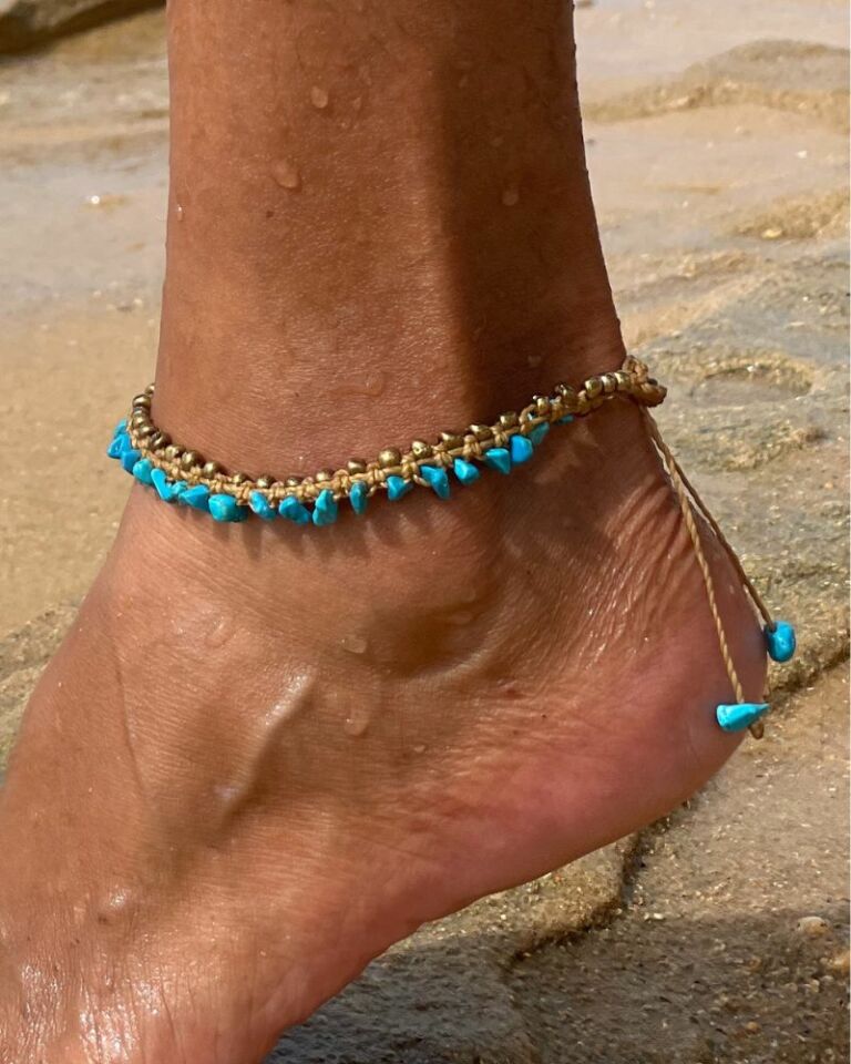 Tornozeleira artesanal com howlita turquesa e macramê dourado usada na praia.
